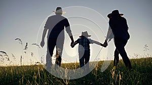 Happy cute family. Parents, father, mother, son are walking across the field in the park at evening sunset. Happy cute