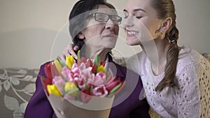 Happy cute girl giving flowers her business grandmother in her 70s.