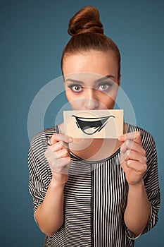 Happy cute girl holding paper with funny smiley drawing