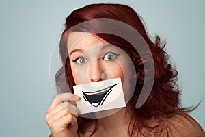 Happy cute girl holding paper with funny smiley drawing