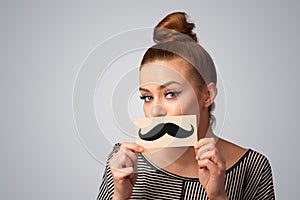 Happy cute girl holding paper with mustache drawing