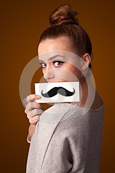 Happy cute girl holding paper with mustache drawing