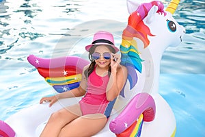 Happy cute girl on inflatable unicorn in  pool