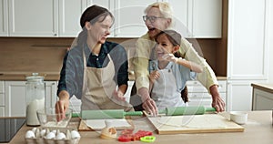 Happy cute girl, mom and grandma having fun in kitchen