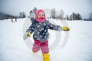 Happy cute girl running down snowy slope.