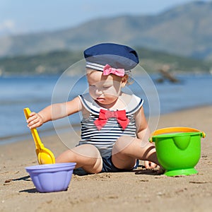 Happy cute girl in swimsuit playing with sand on beach