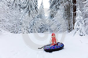 Happy cute healthy little toddler girl on snow tube. Cute little happy child having fun outdoors in winter on colorful