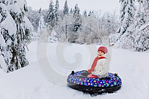 Happy cute healthy little toddler girl on snow tube. Cute little happy child having fun outdoors in winter on colorful