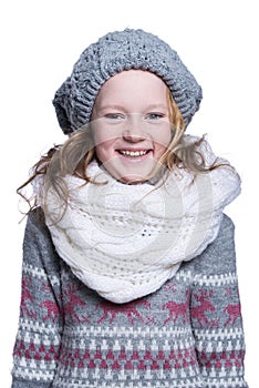 Happy cute kid posing in the studio isolated on white background. Wearing winter clothes. Knitted woolen sweater, scarf, hat
