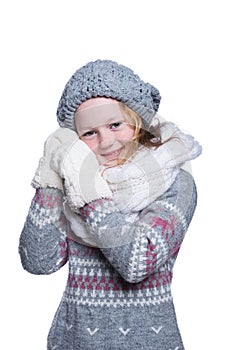 Happy cute kid posing in the studio isolated on white background. Wearing winter clothes. Knitted woolen sweater, scarf, hat.