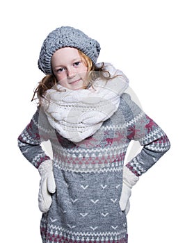 Happy cute kid posing in the studio isolated on white background. Wearing winter clothes. Knitted woolen sweater, scarf, hat.