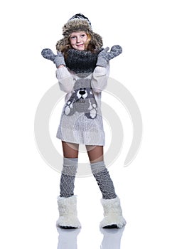 Happy cute kid posing in the studio isolated on white background. Wearing winter clothes. Knitted woolen sweater, scarf, hat.