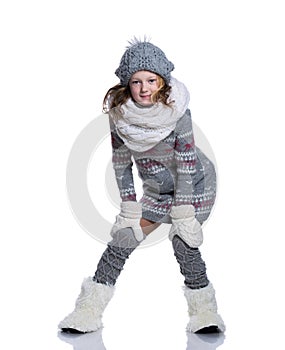 Happy cute kid posing in the studio isolated on white background. Wearing winter clothes. Knitted woolen sweater, scarf, hat