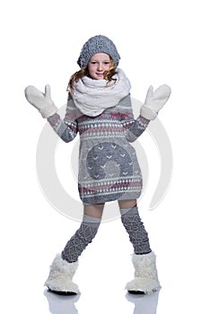 Happy cute kid posing in the studio isolated on white background. Wearing winter clothes. Knitted woolen sweater, scarf, hat.