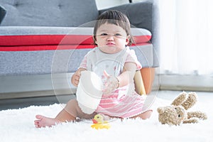 Happy cute little 7 months old multiracial, asian and caucasian, newborn baby girl sitting on floor in living room at home,