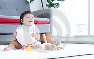 Happy cute little 7 months old multiracial, asian and caucasian, newborn baby girl sitting on floor in living room at home,