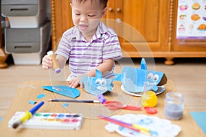 Happy cute little Asian 2 years old toddler boy child enjoying doing arts and crafts at home