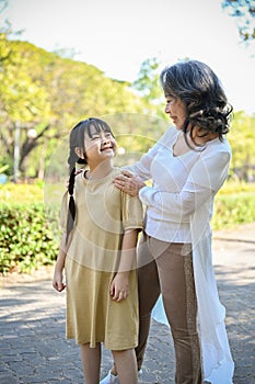 Happy cute little Asian girl or granddaughter having great time with her grandmother in park