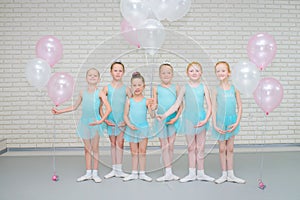 Happy cute little ballet dancers with air ballons smiling at looking at camera at dance school class.