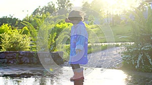 Happy cute little boy chid running playing having fun jumping through puddles in raincoat and rubber boots. laughing and