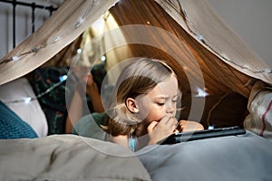 Happy cute little boy playing in a teepee tent at home.