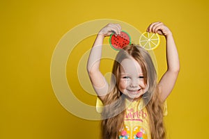 Happy cute little child girl holding slice of fruit over head making ears having fun medium close-up