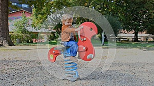 Happy cute little child having fun playing with colorful wooden toys in the park, sunny warm autumn day in children playground