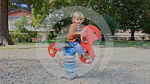 Happy cute little child having fun playing with colorful wooden toys in the park, sunny warm autumn day in children playground