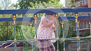 Happy cute little girl climbs on bright playground