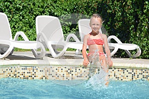 Happy cute little girl having fun in swimming pool on sunny day