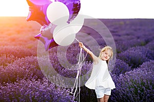 Happy cute little girl in lavender field with purple balloons. Freedom concept.