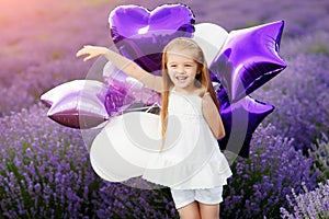 Happy cute little girl in lavender field with purple balloons. Freedom concept.