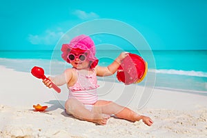 Happy cute little girl play with sand and toys on beach