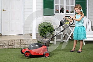 Happy cute little girl with red lawn mower