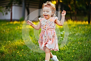 Happy cute little girl running on the grass in the park. Happiness