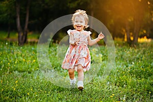 Happy cute little girl running on the grass in the park. Happiness.