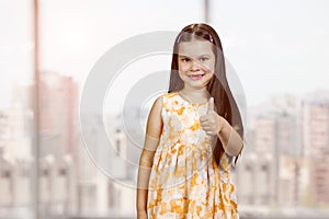 Happy cute little girl is showing thumb up.