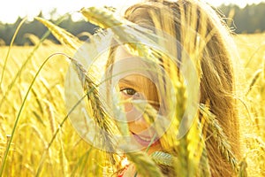 Happy cute little girl smiling on the field at sunset. Happy girl on nature.