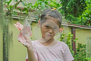 Happy cute little girl smiling and holding cash money in hand.