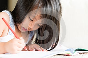 Happy cute little girl smiling and holding red pencil