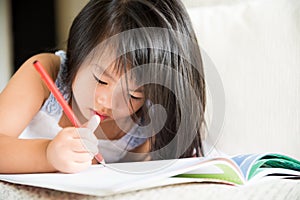 Happy cute little girl smiling and holding red pencil