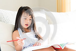 Happy cute little girl smiling and holding red pencil