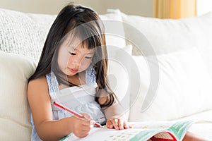 Happy cute little girl smiling and holding red pencil