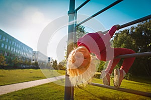 Happy cute little girl upside down on monkey bars