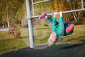 Happy cute little girl upside down on monkey bars