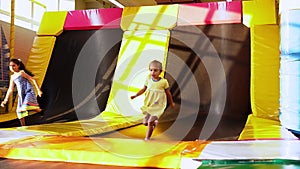 Happy Cute Little Preschool Tinaiger Girls runing joyfully in Playroom. Children Jump on Trampolines in Kids