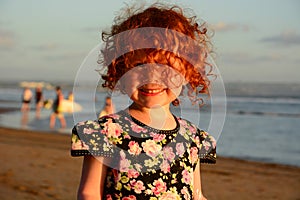 Happy Cute little redhead girl on the Bali beach. Sunset