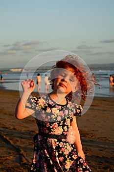 Happy Cute little redhead girl on the Bali beach. Sunset
