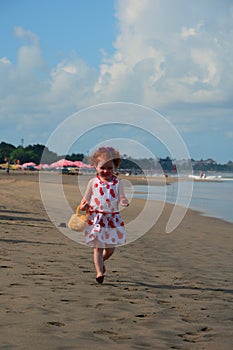 Happy Cute little redhead girl runs on the Bali beach