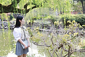 Happy cute lovely beautiful young girl high school college student enjoy free time read a book by a lake in summer park